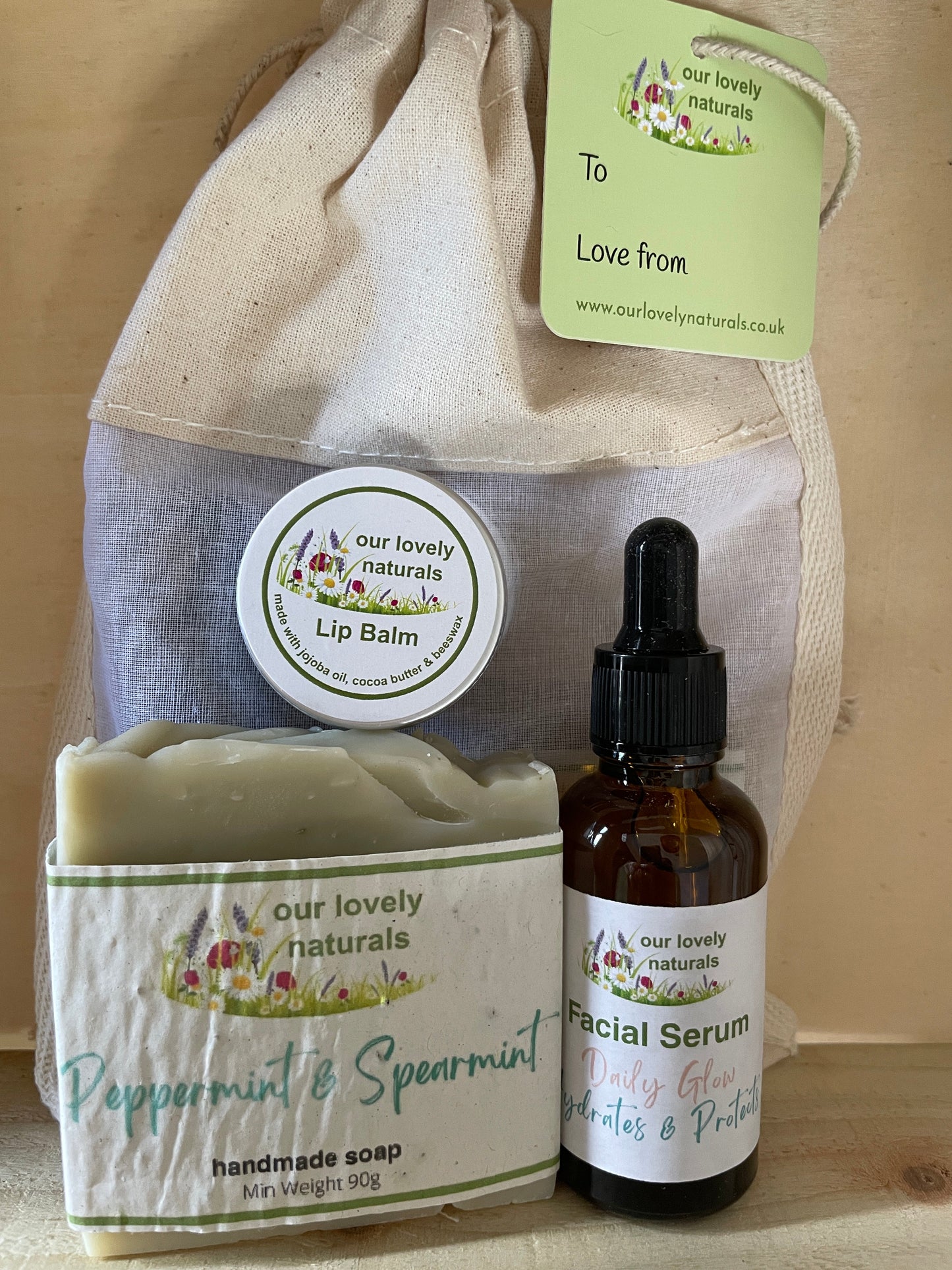 Set of skincare products including soap, lip balm, and facial serum from 'our lovely naturals' on a wooden surface.