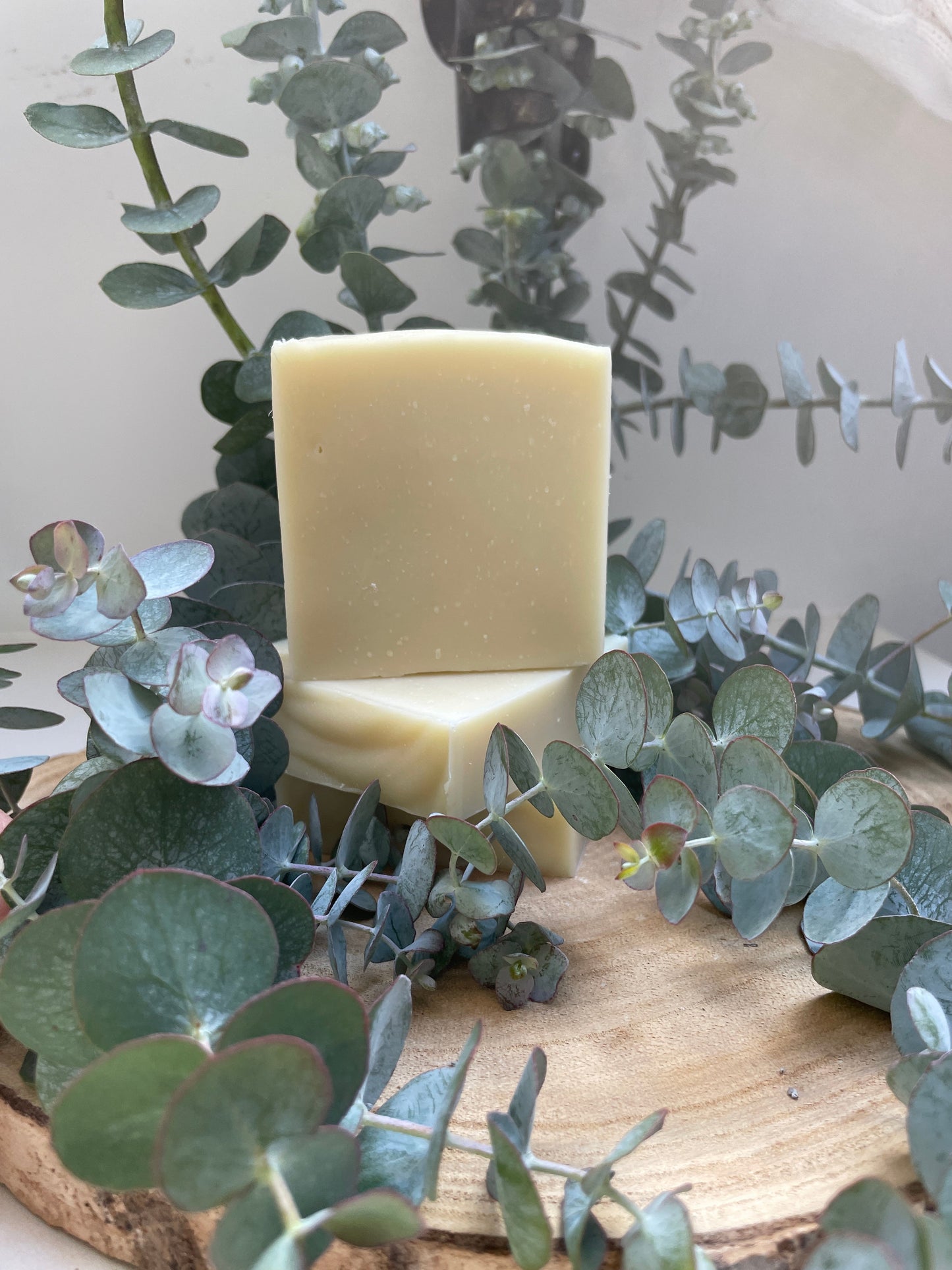 Bar of soap on a wooden block with eucalyptus leaves