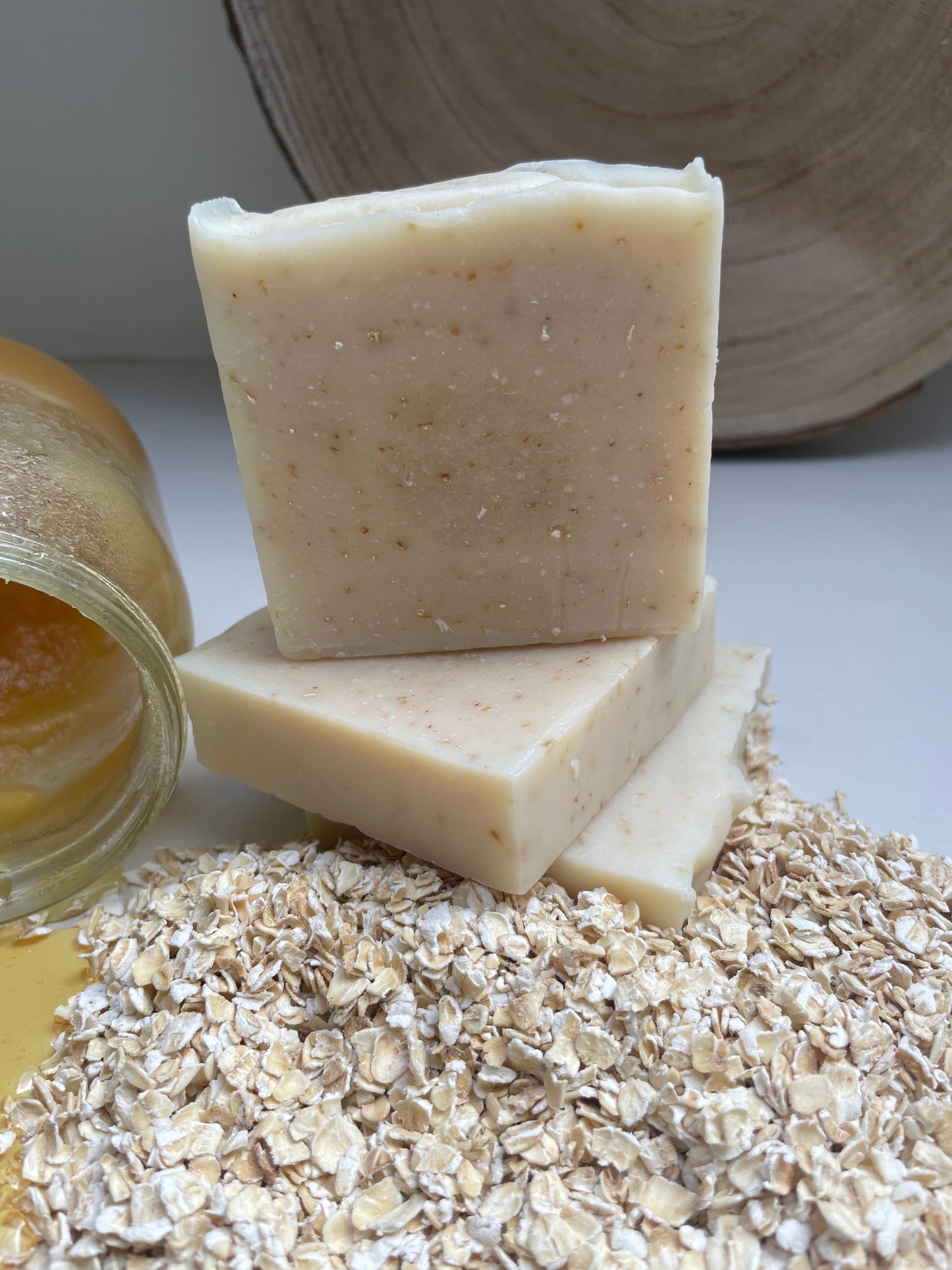 Environmentally friendly handmade natural honey & oat soap bars containing honey and oats. Displayed with a jar of honey and loose oats.