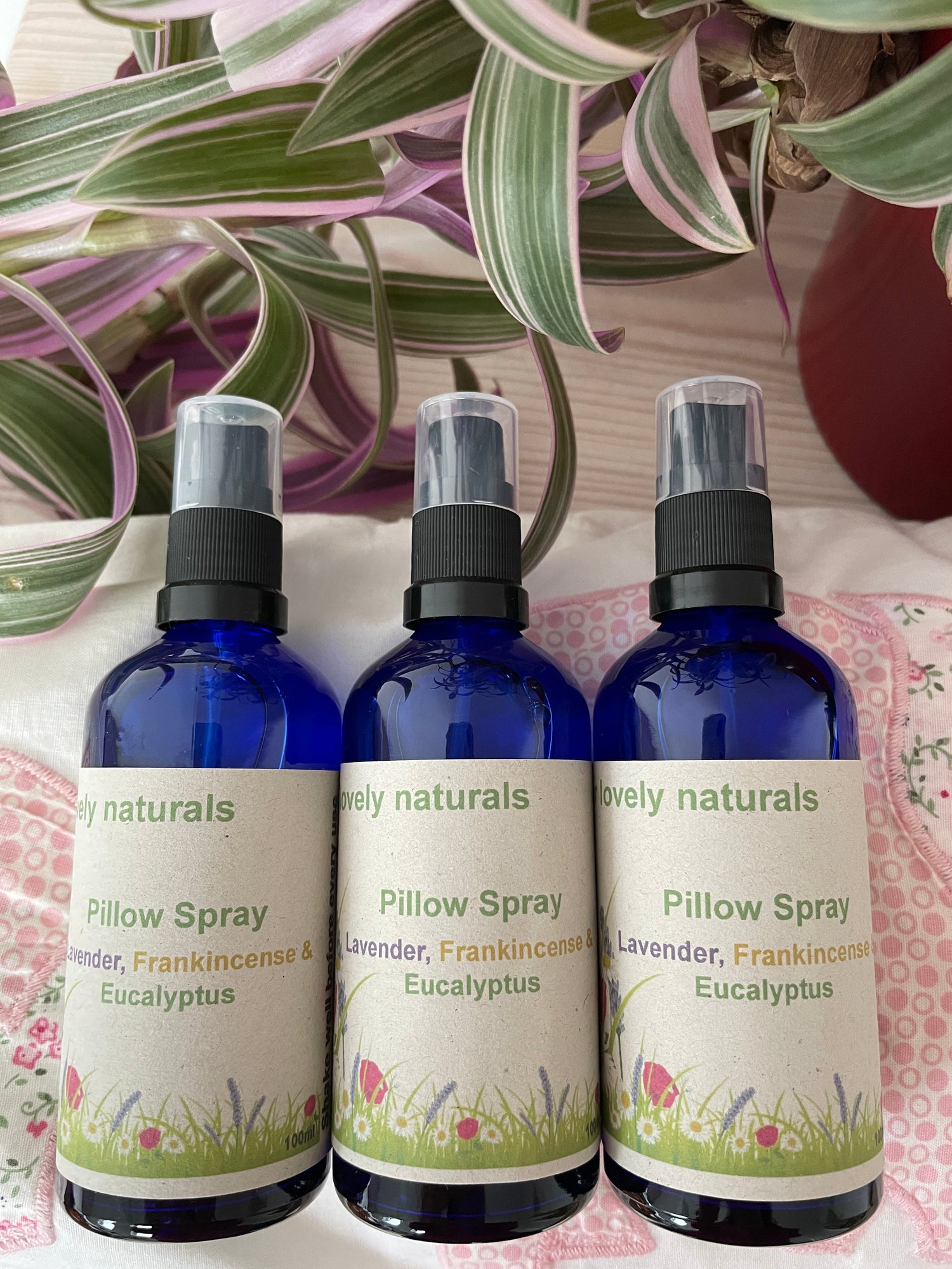 Three blue spray bottles of natural environmentally friendly pillow and linen spray made with fragrant lavender, frankincense and eucalyptus.