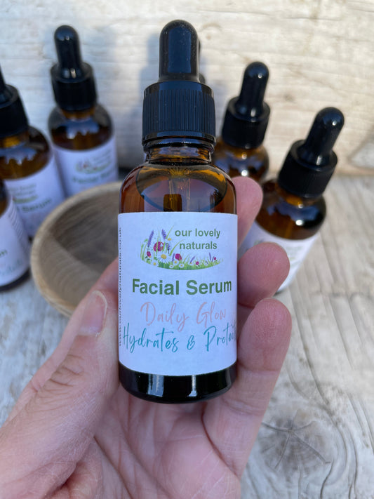 Facial serum - Daily Glow bottle held in hand with 'our lovely naturals' branding, surrounded by more serum bottles.